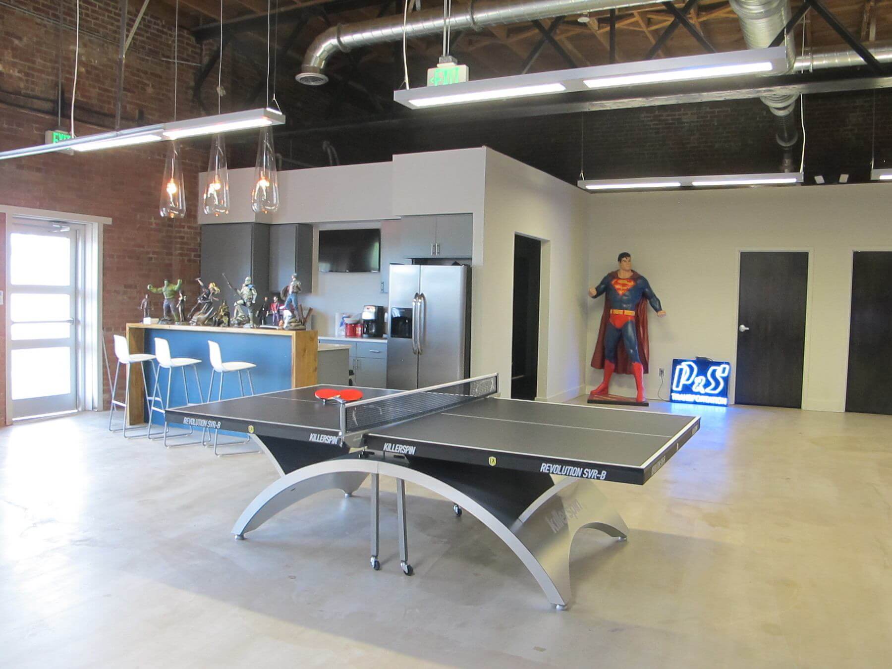 This break room boasts multiple comic heroes as well as a state-of-the-art ping-pong table for when you need to wipe your mental slate clean with a good old game of ping-pong