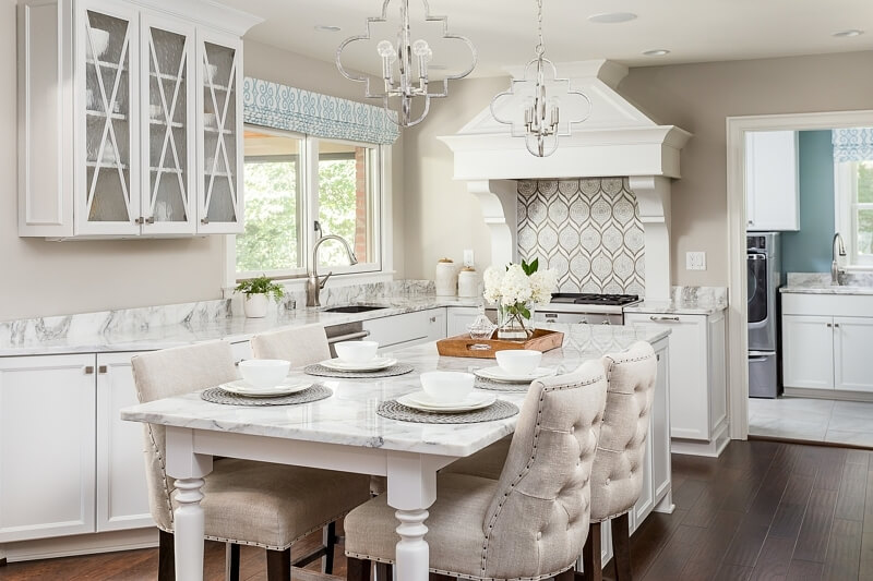 The hood, backsplash, gorgeous marble countertops, custom cabinetry and adorable seating area have us swooning!