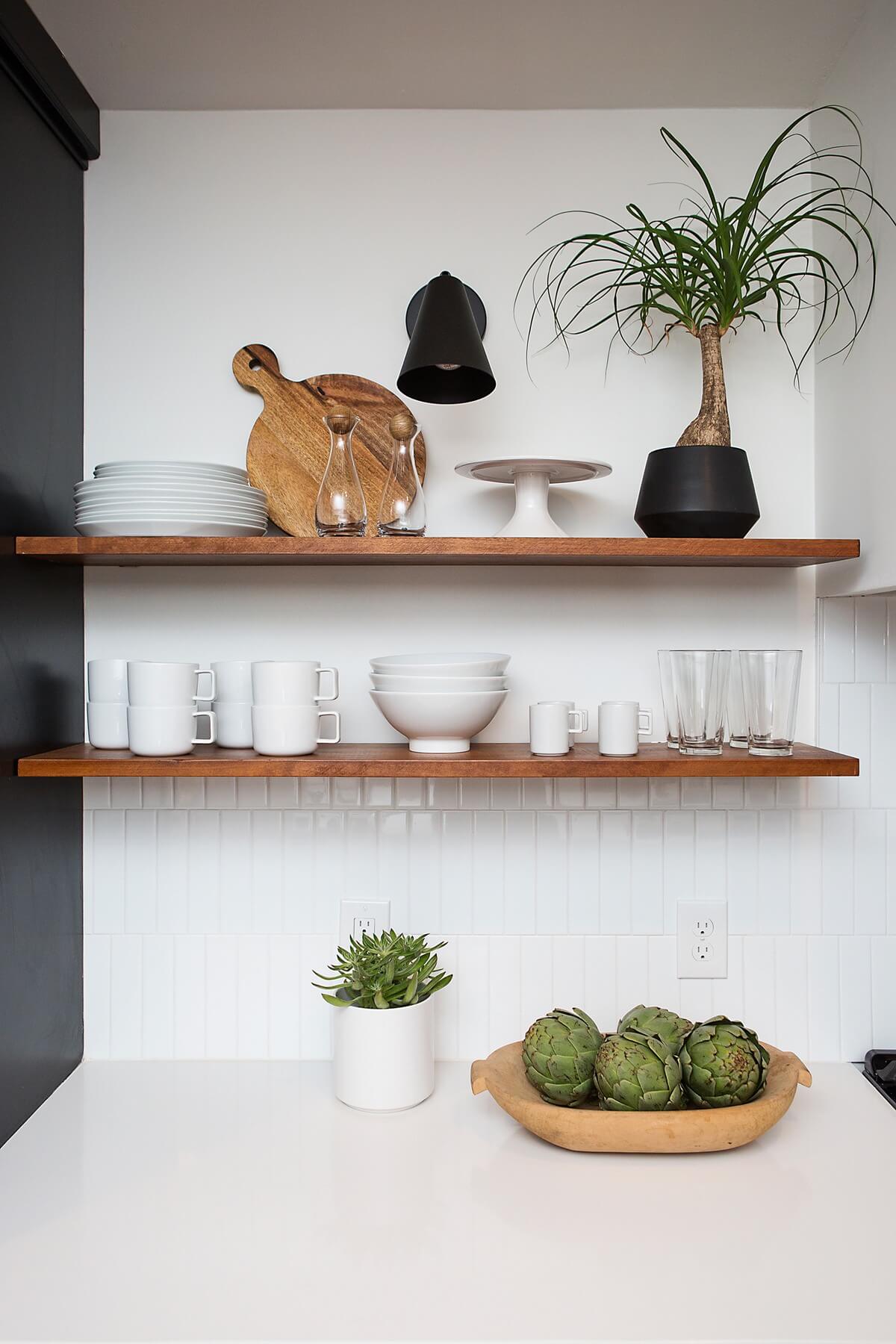 We love the delicate little black sconce over the wooden floating shelves. Image: Ashley Lauren Studios