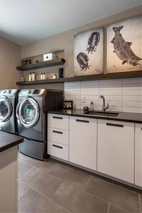 Laundry room with artwork on shelving and washer/dryer