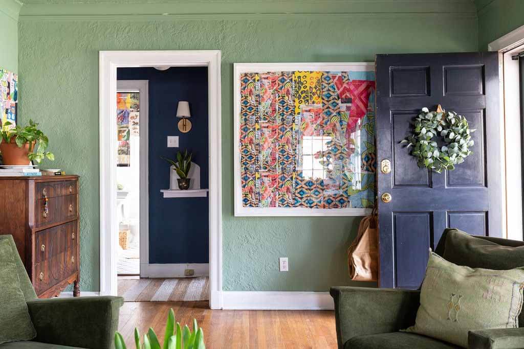 Living room with muted green walls and colorful art